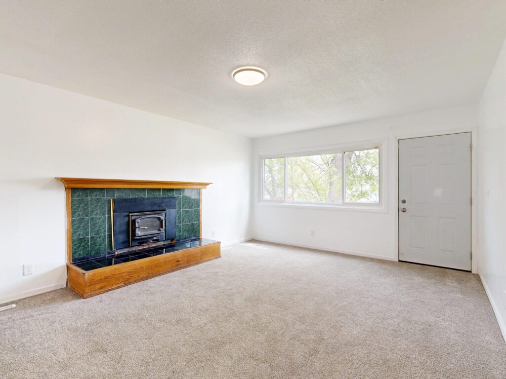 Bright empty living room featuring a modern fireplace and large window view.
