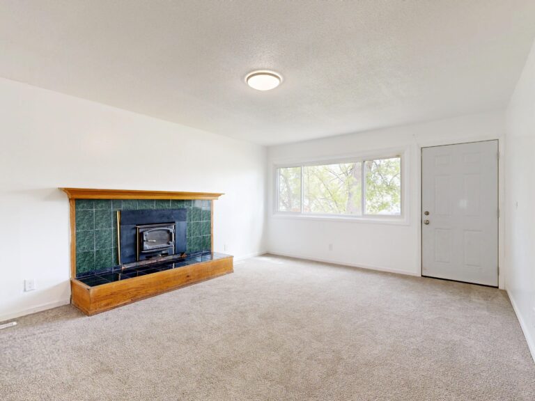 Bright empty living room featuring a modern fireplace and large window view.